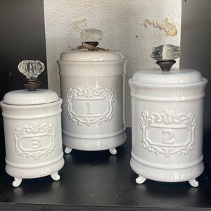 Mud Pie 3 piece canister set with glass knobs on top and 1,2,3 on the front.